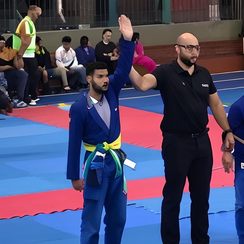There are two people standing on a blue carpet with one person raising their hand, torneio de artes marciais, competition winning, icaro carvalho, torneio, Directed by: Luis Miranda, Caroline Gariba, awar vencendo, 2 0 1 9, 2019, Mina Petrovic, olhar orgulhoso, competition highlights, diego fernandez, fernanda suarez