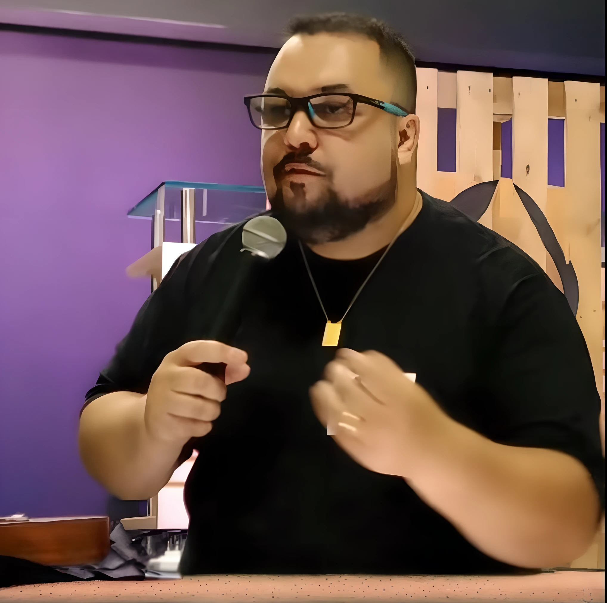 Homem de camisa preta segurando um microfone e parado em frente a uma parede roxa, david rios ferreira, andres rios, victor maristane, José Moncada, Cristiano Orrillo, Joel Torres, Directed by: Nandor Soldier, danilo torres, ástor alexander, Miguel Vicente, luiz escanuela, henry ascensio