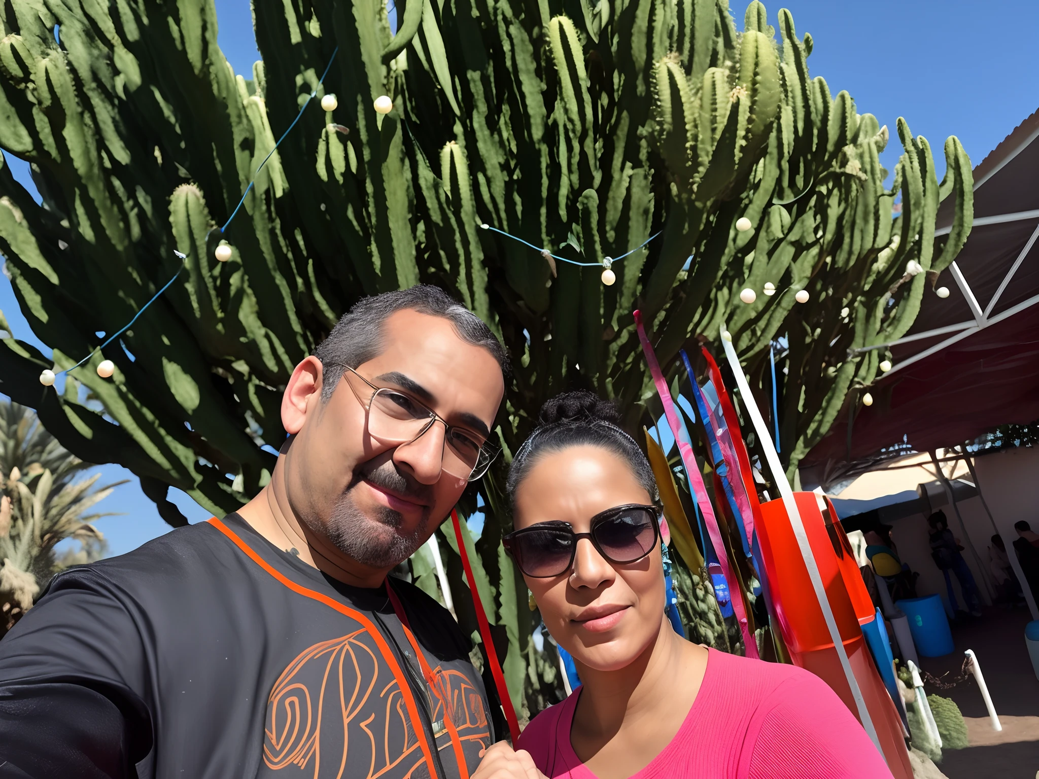 They are posing for a photo in front of a cactus, em Chuquicamata, em jardins de maconha, segurando um cacto, next to some alien plants, cactus and pearls over the head, vacation photo, lindo dia ensolarado, festival, imagem do avatar, cactos em todos os lugares, feito de espinhos de cacto, In Sao Paulo, imagem de perfil