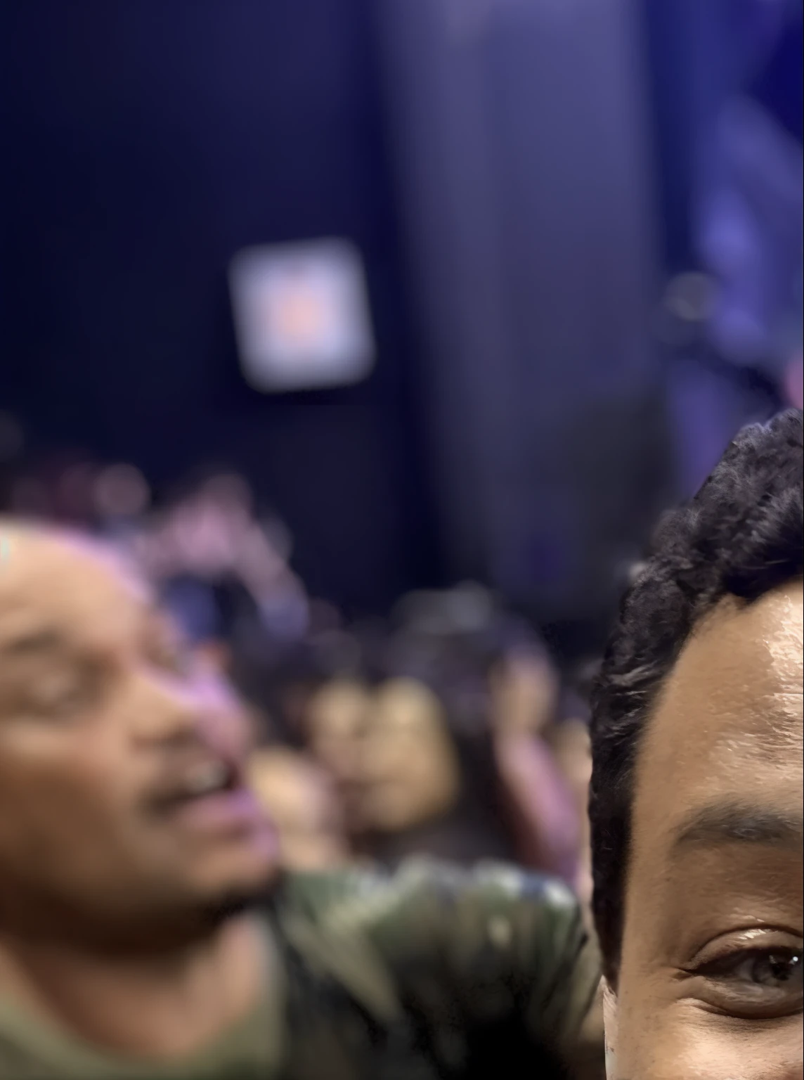 Smiling man taking a selfie in front of a crowd of people, taken in the early 2020s, ligeiramente sorridente, Aaron Sims, rosto suado, foto do perfil, muito ligeiramente sorridente, cara de aposta, auto - sorriso satisfeito, audience selfie, audience in the background, parecendo feliz, foto de perfil 1024px, muito animado, Forrest em segundo plano