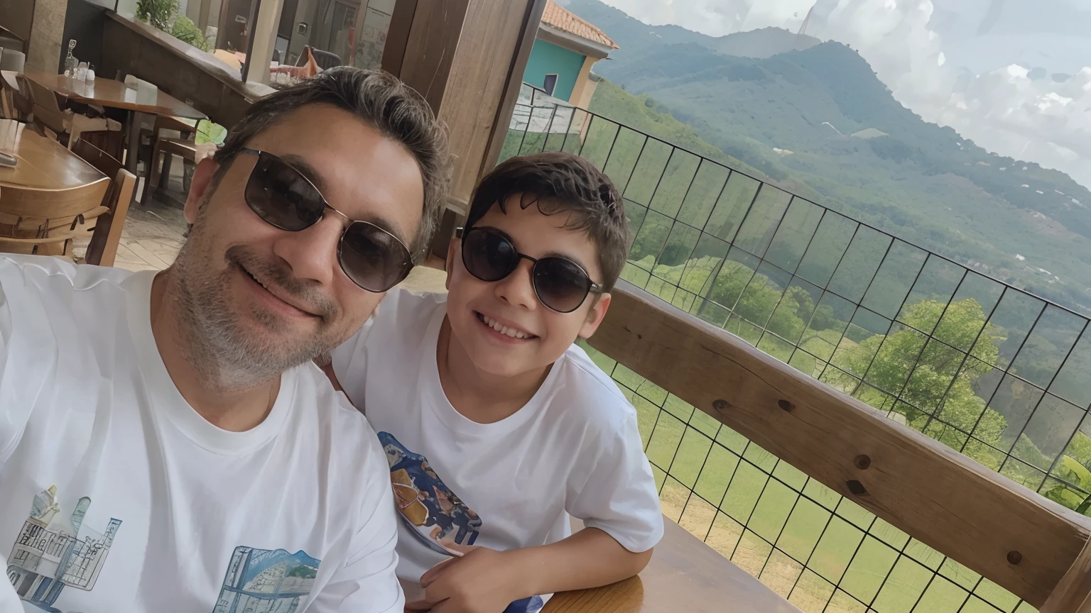 Eu e meu filho no restaurante com camiseta beanca e sorrindo com paisagem ao fundo