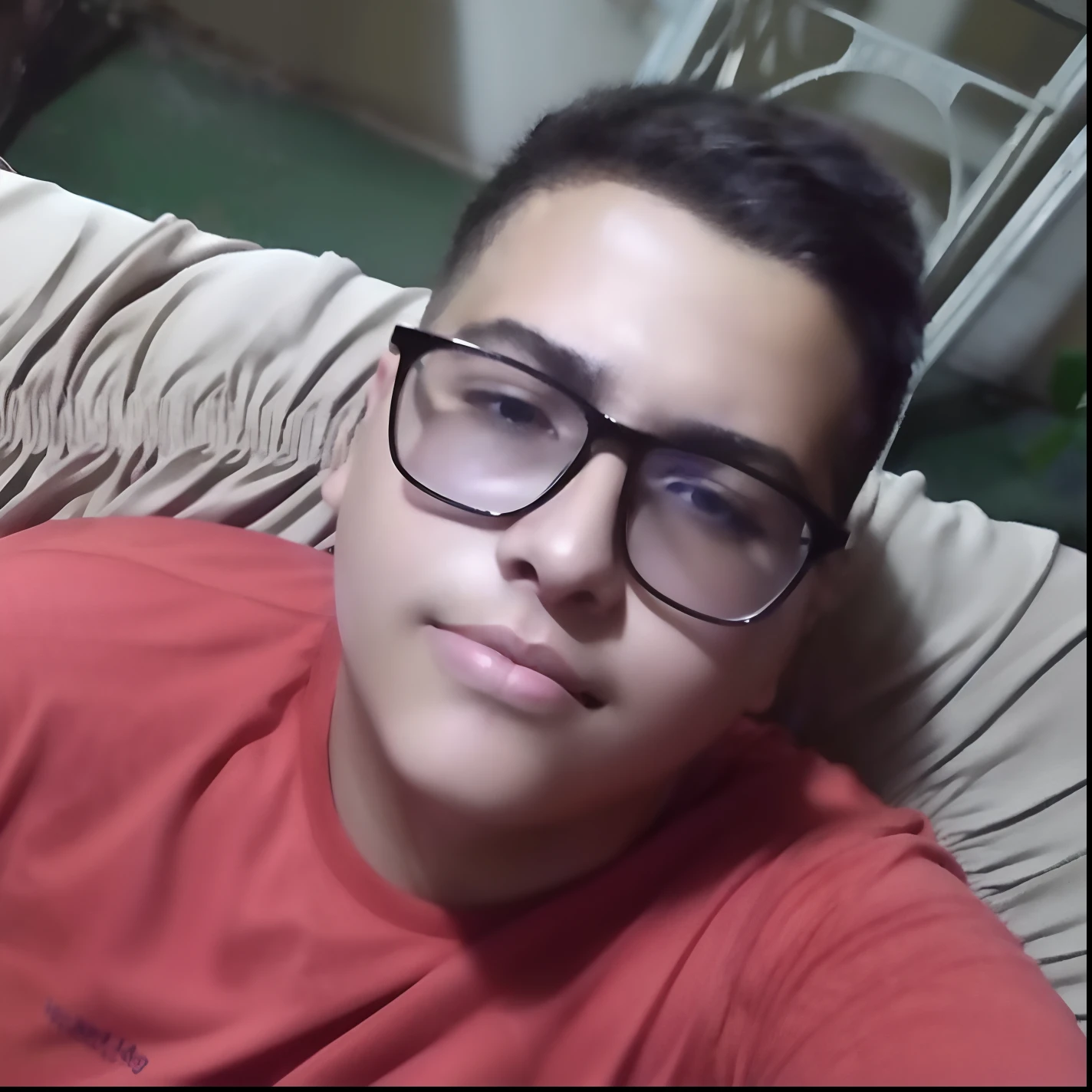 There's a man with glasses lying on a couch, em torno de 1 9 anos, usando terno azul escuro