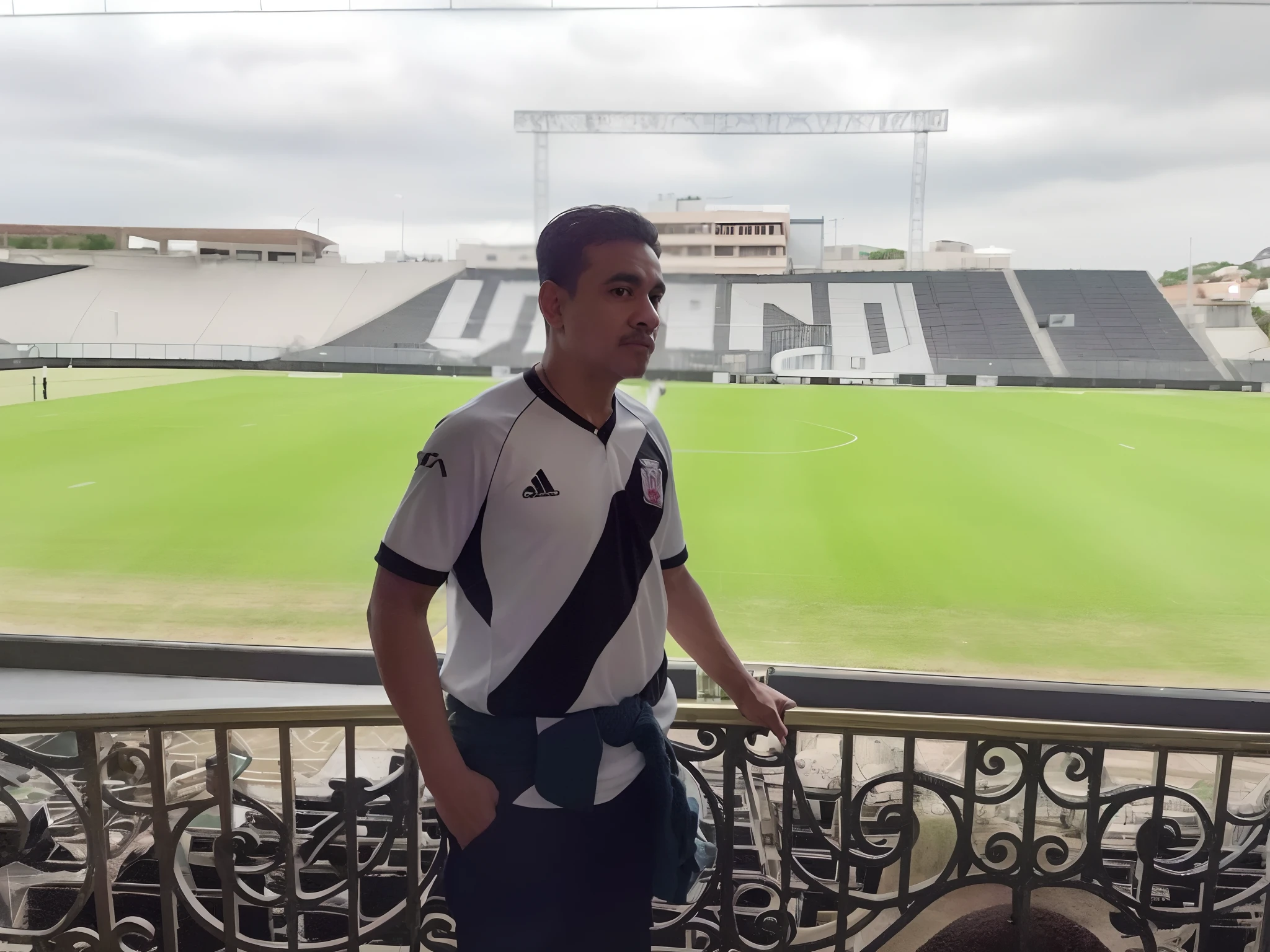 There is a man standing on a balcony with a football field in the background, Sao Januario Stadium k, standing in a stadium, com uma cidade em segundo plano, inspirado em Oswaldo Viteri, daniel mirante, mateus 9 5, caio santos, luiz escanuela, desporto, inspired by Raúl Martínez