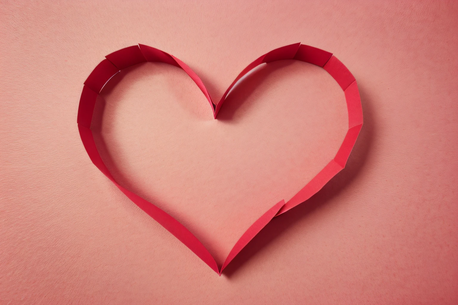 Layered red paper cut heart on a pink background. Heart in all shades of red color on light pink background.