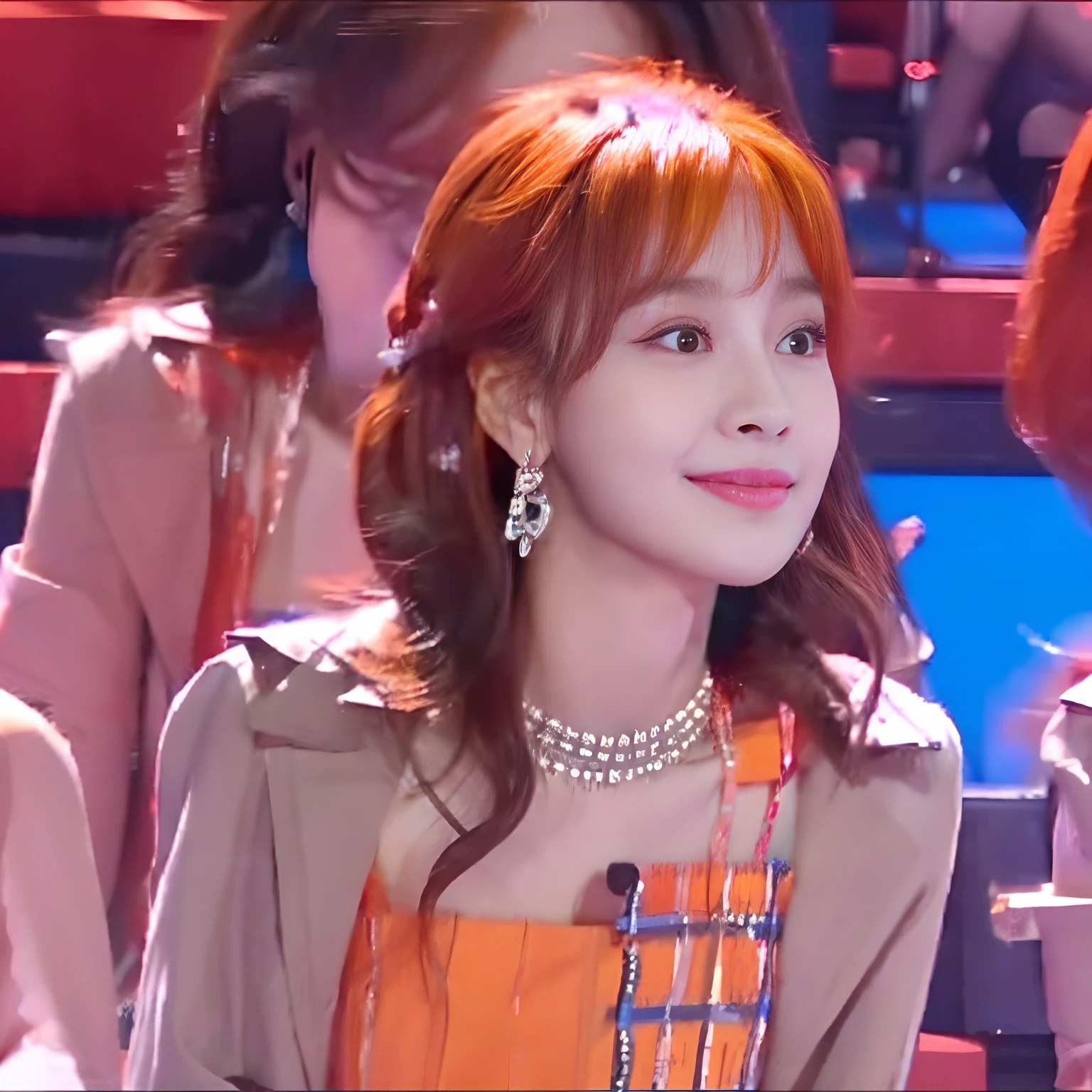 1girl, kpop idol, orange hair, straight layered hairstyle, bangs, alluring eyes, Fancam from within the audience, camera pointed slightly up towards idol from beneath, performance Fancam, pastel frilly mini dress, debut stage