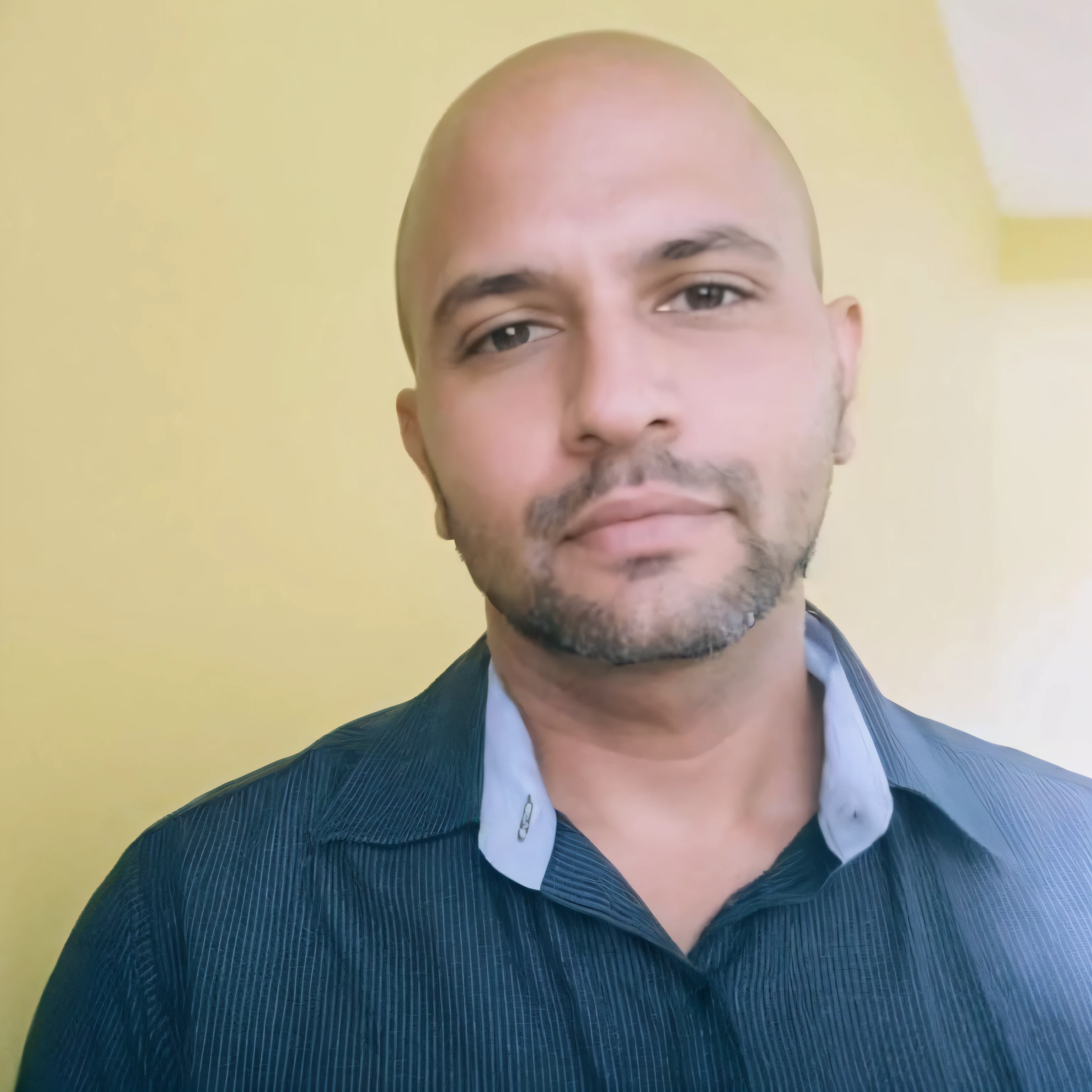 Light brunette man with bald head and blue shirt standing in front of a yellow wall, com barba, sem capacete, Homem de 40 anos, Mohamed Chahin, careca com barba curta, foto portait foto de perfil, Afonso Azpiri,   foto de perfil profissional, com rosto preciso