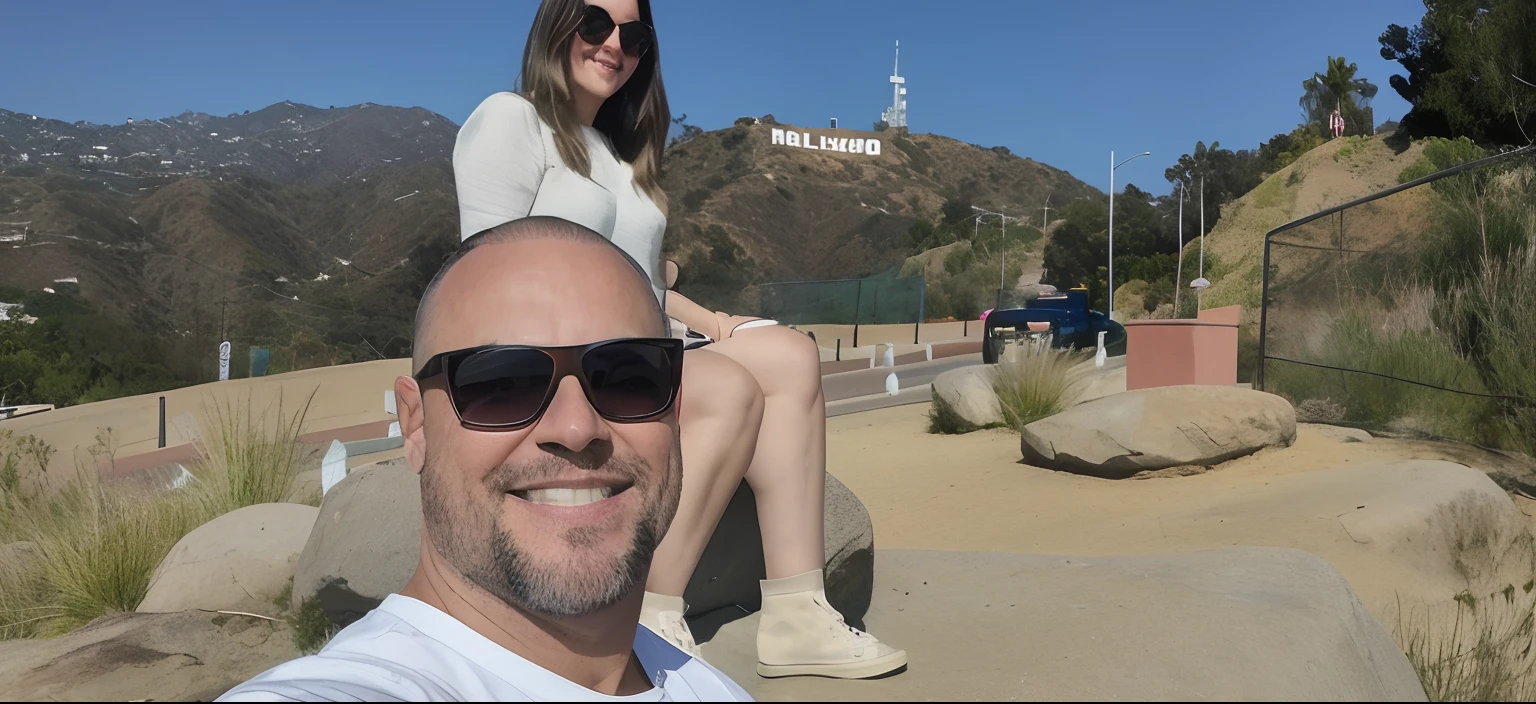 There's a man and a woman sitting on a rock in front of a Hollywood sign, Hollywood, 🤬 🤮 💕 🎀, Carro Mulholland, Los Angelos, Los Angeles California, 💋 💄 👠 👗, Directed by: Tom Wänerstrand, cena Hollywood, fotografia de perfil, Los Angeles 2 0 1 5, Colinas ao fundo, fotografia, holiday photography