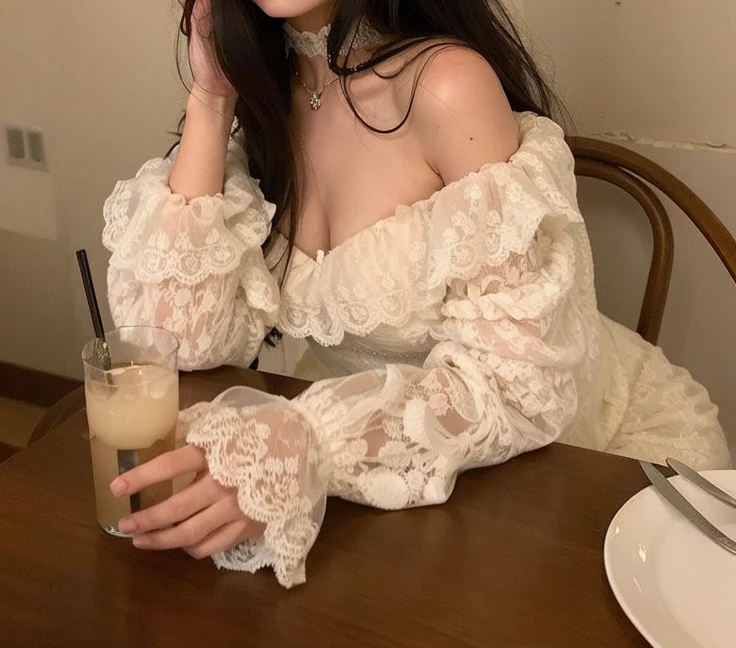 There's a woman sitting at a table with a drink, renda branca, vestido com um babado ((renda)), renda, vestido de renda, vestido com rendas brancas intrincadas, roupas brancas de renda, top chique, vestido de renda branco, mangas bufantes, linda senhora, vestido rendado, Lacey, romantic gown, intrincado e detalhado conjunto de rendas, roupa intrigante, 8k))
