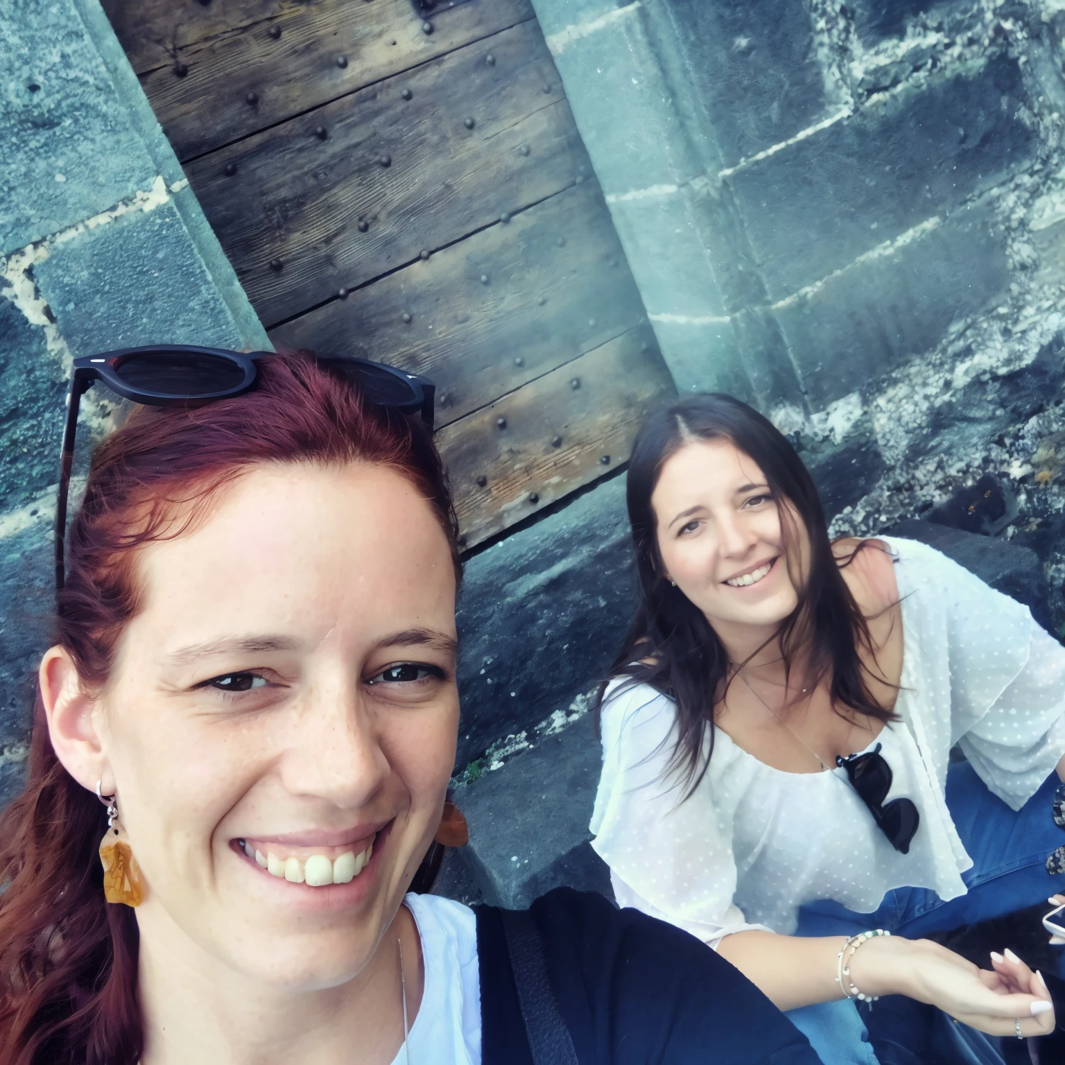 there are two women sitting on the ground taking a selfie, walking in a castle, sitting in a castle, in a castle, on a bridge, with a castle in the background, very very happy!, with godray, in the colosseum, having a great time, having a good time, standing near a castle, selfie, ( castle in the background )