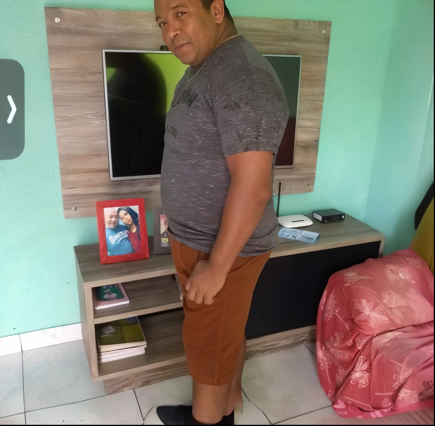 There's a man standing in front of a TV in a living room, ele tem cerca de 50 anos, ele tem cerca de 5 0 anos de idade, ele tem cerca de 60 anos, ele tem cerca de 6 0 anos de idade, ele tem cerca de 4 0 anos de idade, ele tem cerca de 40 anos, Ronaldo Nazario Fenomeno, Homem de 4 0 anos