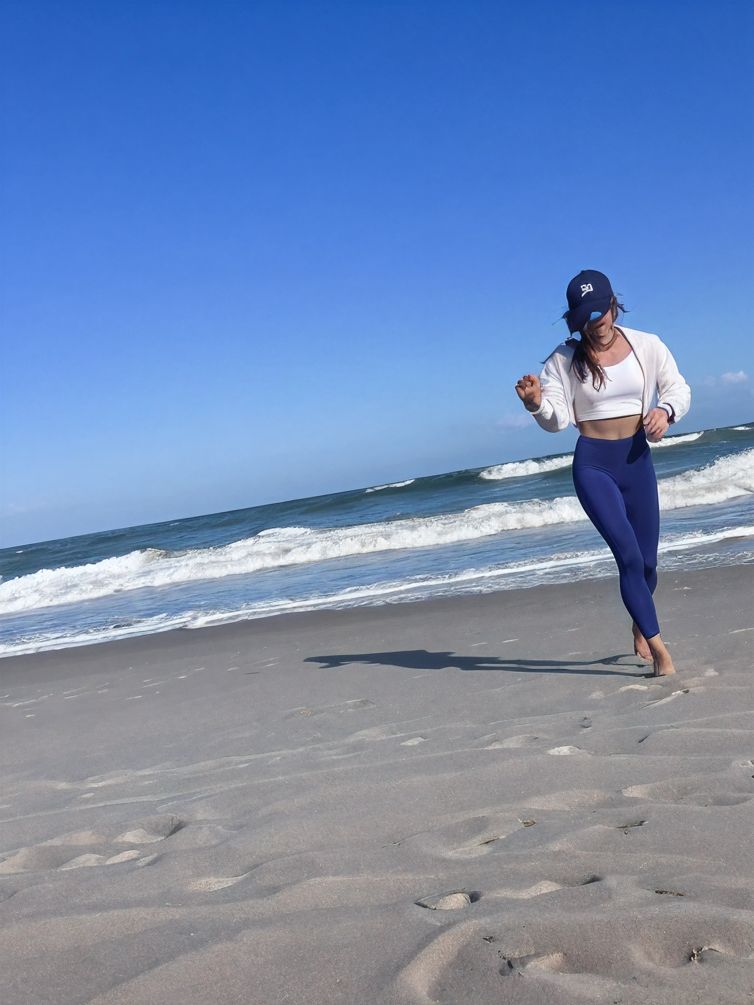 there is a woman running on the beach with a hat, posando em uma praia com o oceano, standing at the beach, standing near the beach, ao lado do oceano, O oceano ao fundo, na praia, Standing on a beach, posando na praia, foto de praia, na praia, em uma praia, oceano ao fundo