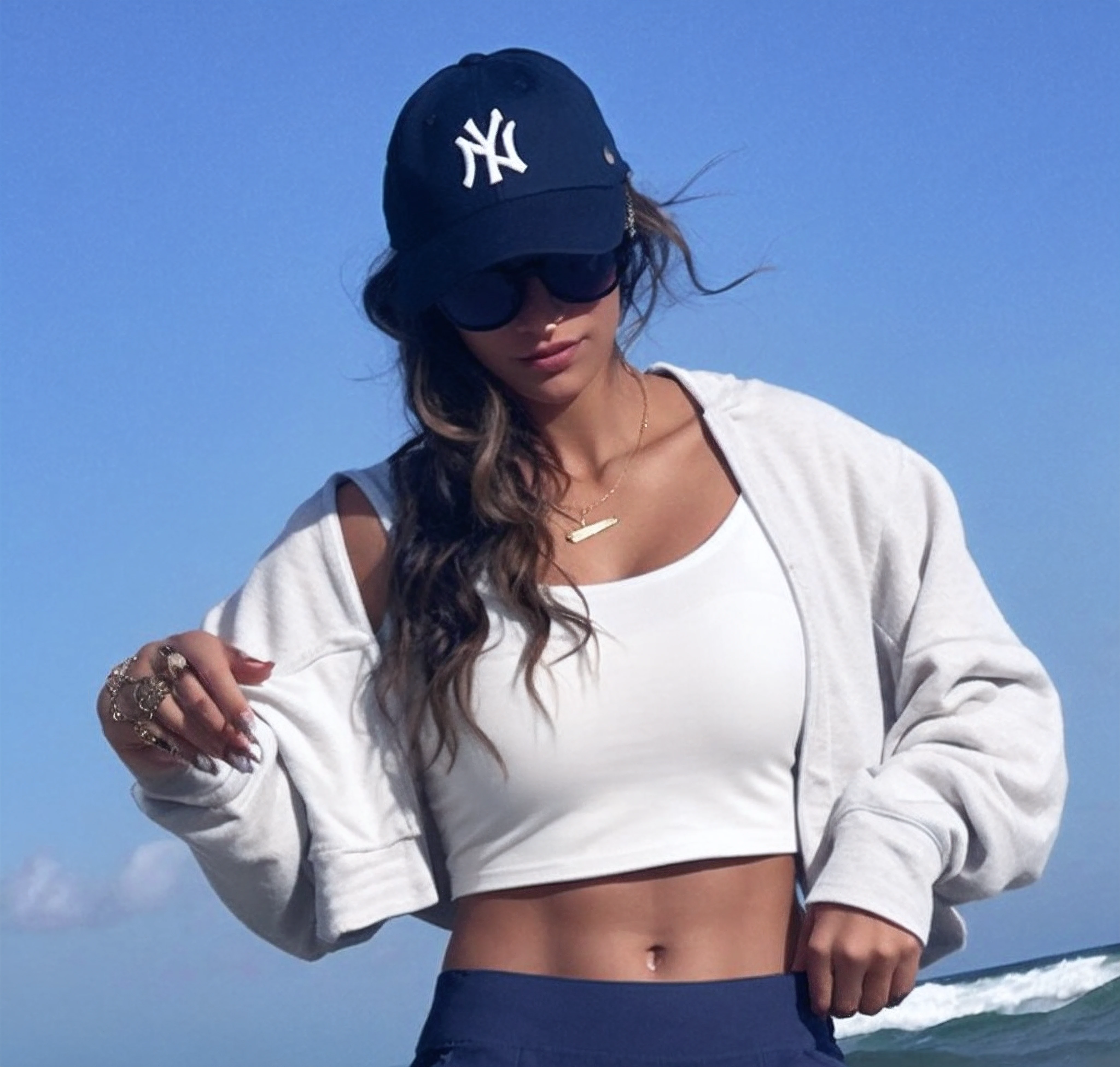 mulher de camisa branca e bermuda azul na praia, wearing sunglasses and a cap, her navel is exposed, wearing a navy blue utility cap, tinyest midriff ever, wearing sunglasses and a hat, wearing a chocker and cute hat, sport bra and dark blue shorts, Camisa de corte e abdominais fortes, usando um top cropped sexy