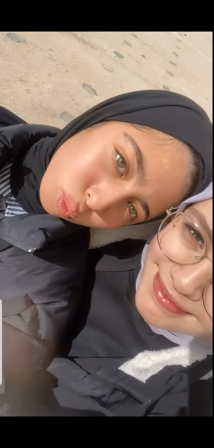 Two women taking a photo wearing a hijab