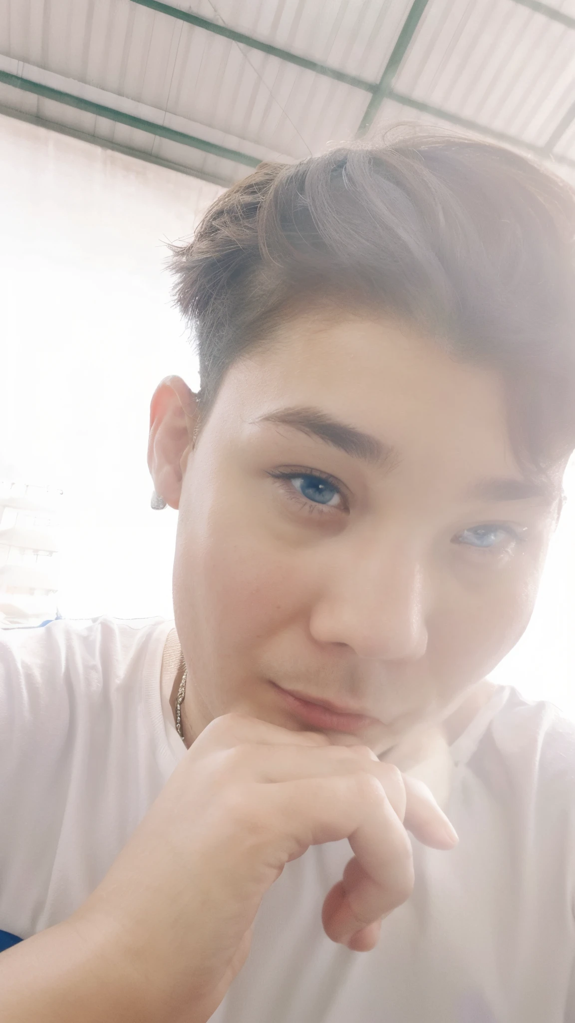 A fat boy with blue eyes looks at the plane from the airport fence