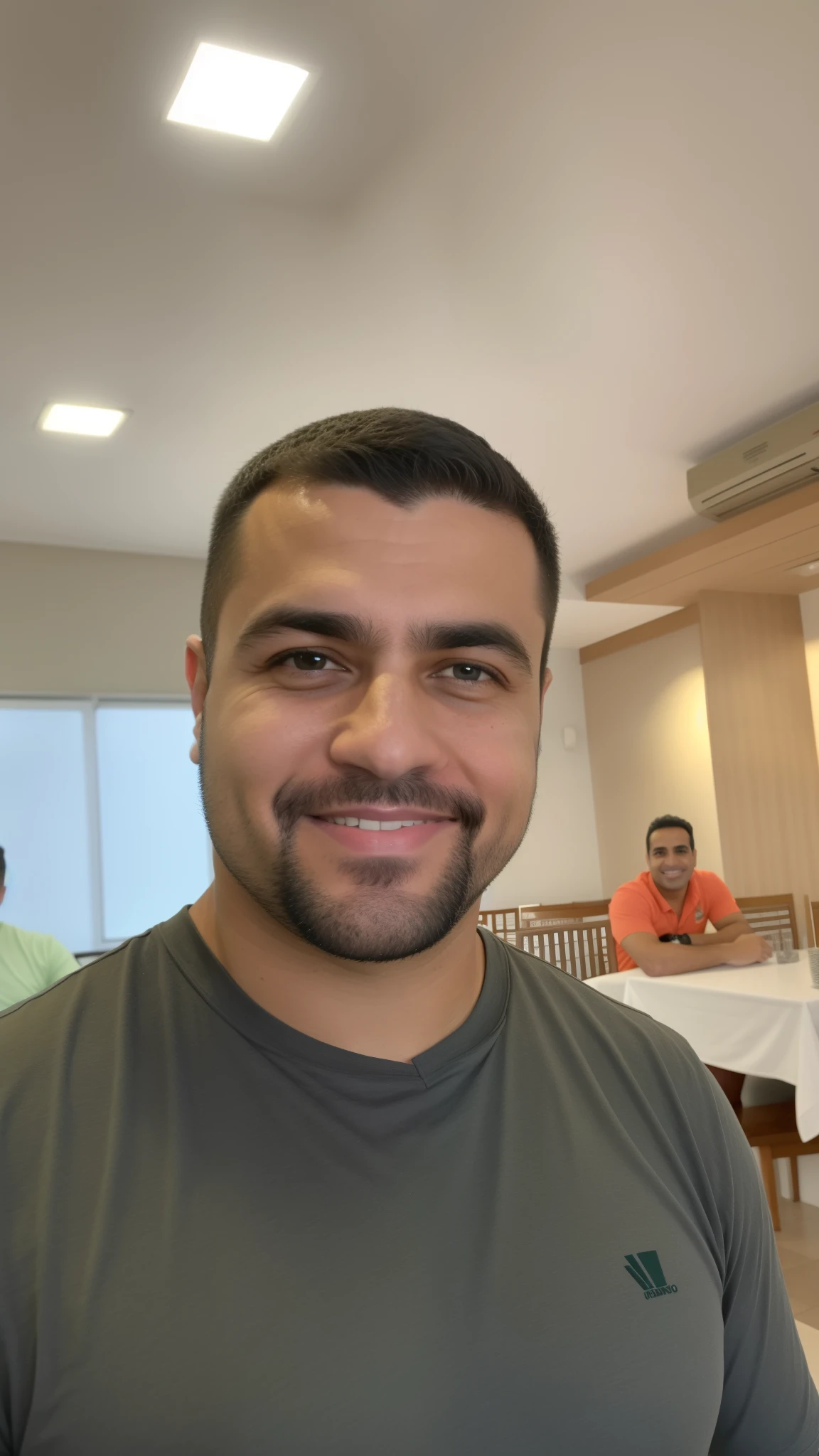 homem sorridente de camisa cinza em um restaurante com pessoas sentadas em mesas, david rios ferreira, Henry Alvim Correa, icaro carvalho, Carmelo Blandino, Directed by: Nandor Soldier, gui guimaraes, cerca de 3 5 anos, edu souza, ástor alexander, George Doutsiopoulos, Homem de 4 0 anos