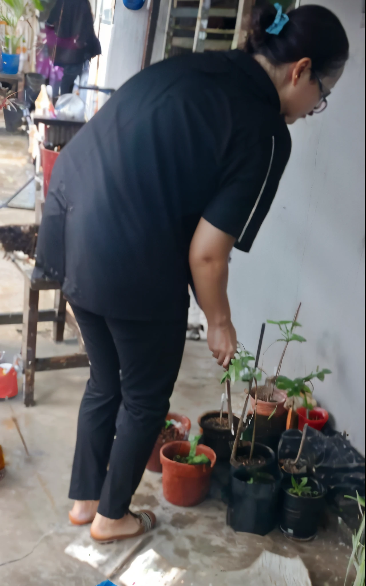 woman in black shirt and black pants standing on cement floor next to potted plants, low quality photo, in garden, tending on arstation, tending on art station, plants growing, very very low quality picture, next to a plant, gardening, semi realism, filled with plants, old picture, potrait, captured with sony a3 camera, photoshot, blurry image