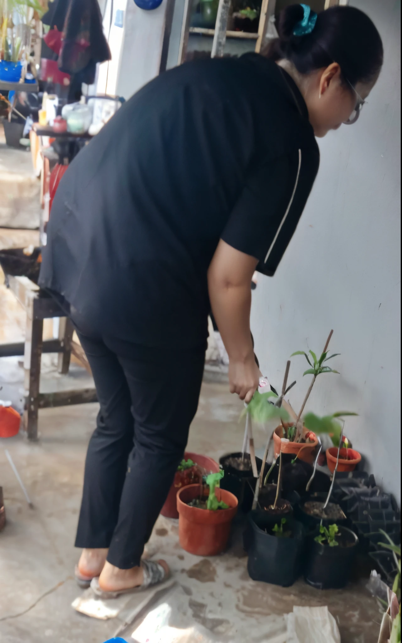 woman in black shirt and black pants standing on cement floor next to potted plants, low quality photo, in garden, tending on arstation, tending on art station, plants growing, very very low quality picture, next to a plant, gardening, semi realism, filled with plants, old picture, potrait, captured with sony a3 camera, photoshot, blurry image