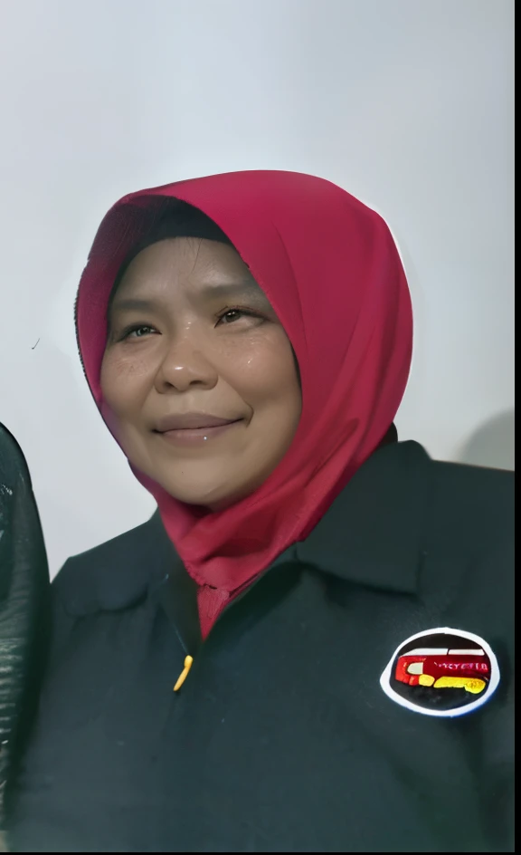 A 50 year old Indonesian woman, wearing a red hijab and black jacket, smiling, with brown skin