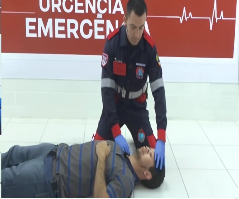 A man lying on the floor being assisted by a paramedic in an emergency situation. The scene is powerful and portrays the injured and bloodied man fighting for his life..