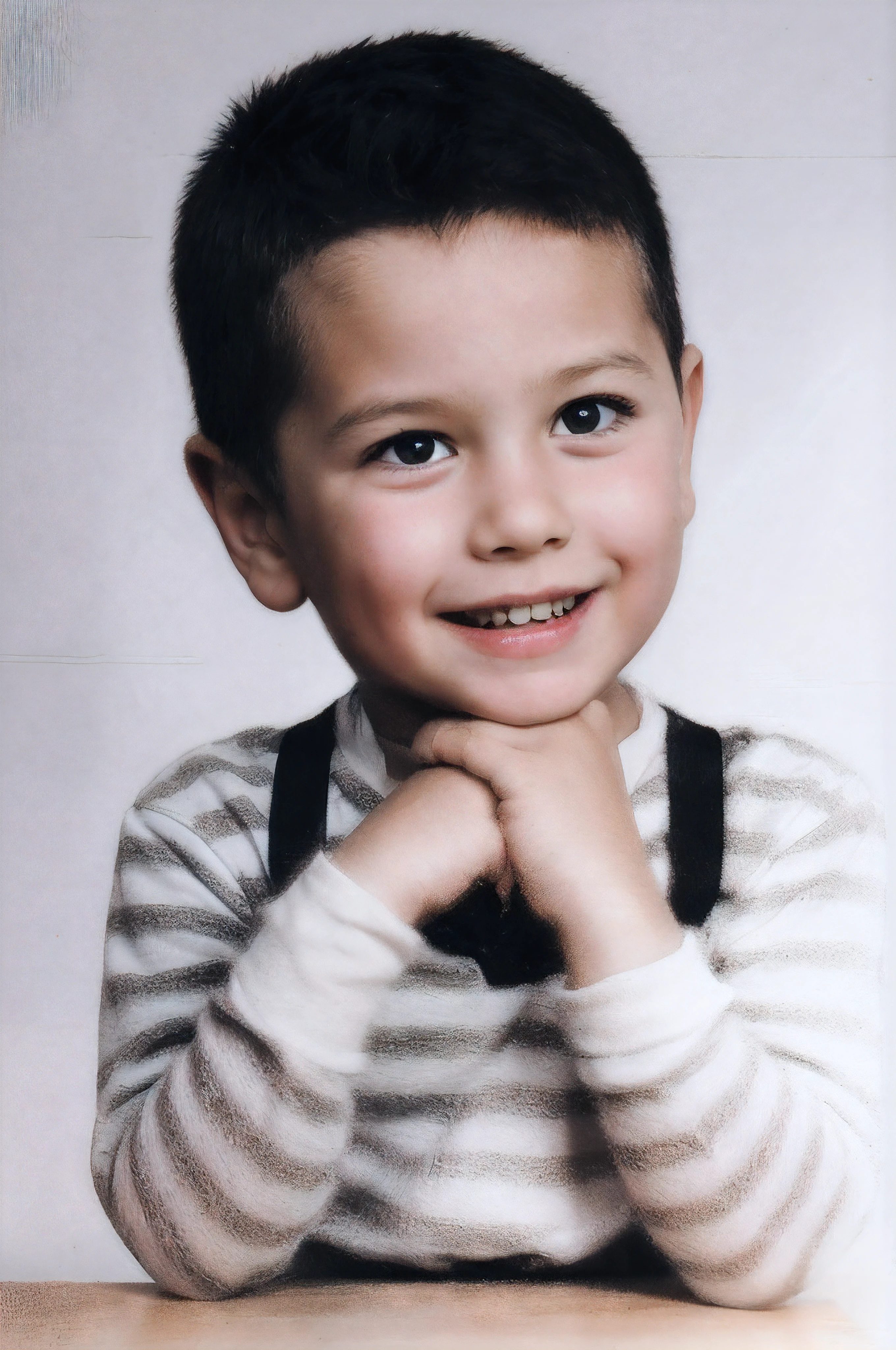 de 7 anos com cabelo preto, (hazelnut eyes), sorridente, shirt with white and black stripes and black suspenders, hands on top of each other, sobre uma mesa de madeira