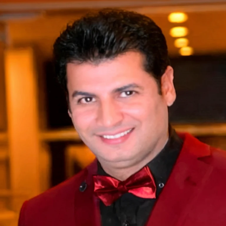 smiling man in red suit and bow tie standing in a room, ahmad merheb, eytan zana, mohamed chahin, amr elshamy, sam nassour, farid ghanbari, hicham habchi, sayem reza, enes dirig, richard taddei, jamel shabbaz, mohamed reda, nekro petros afshar