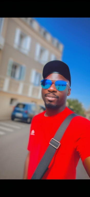 il y a un homme portant des lunettes de soleil et un tee-shirts rouge debout dans la rue, afro-american, Good quality video, Poor quality images, Photo de profil, taken in the early 2020s, George Pemba, album photo, Photographie selfie 8k, Very very good quality image, porter des lunettes de soleil et une casquette, Photo de profil, high quality image