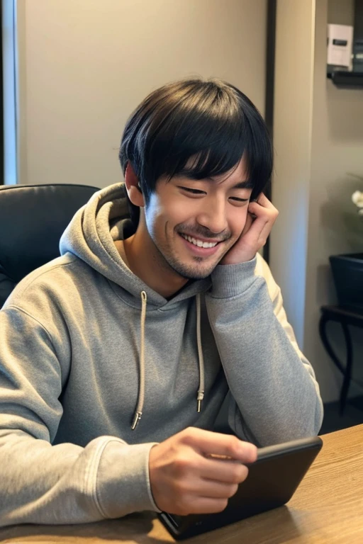Smiling handsome Japanese man absorbed in his smartphone,inside in room,wearing hoodies,I have a smartphone