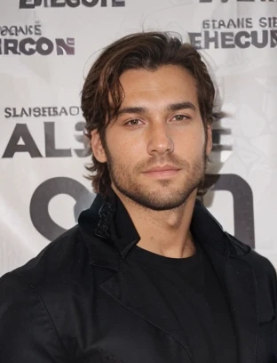 Un jeune homme de 24 ans, un peu bronzé, barbu. Sa mâchoire est assez carrée. Il est châtain. Musclé mais pas trop. Style assez classe et élégant