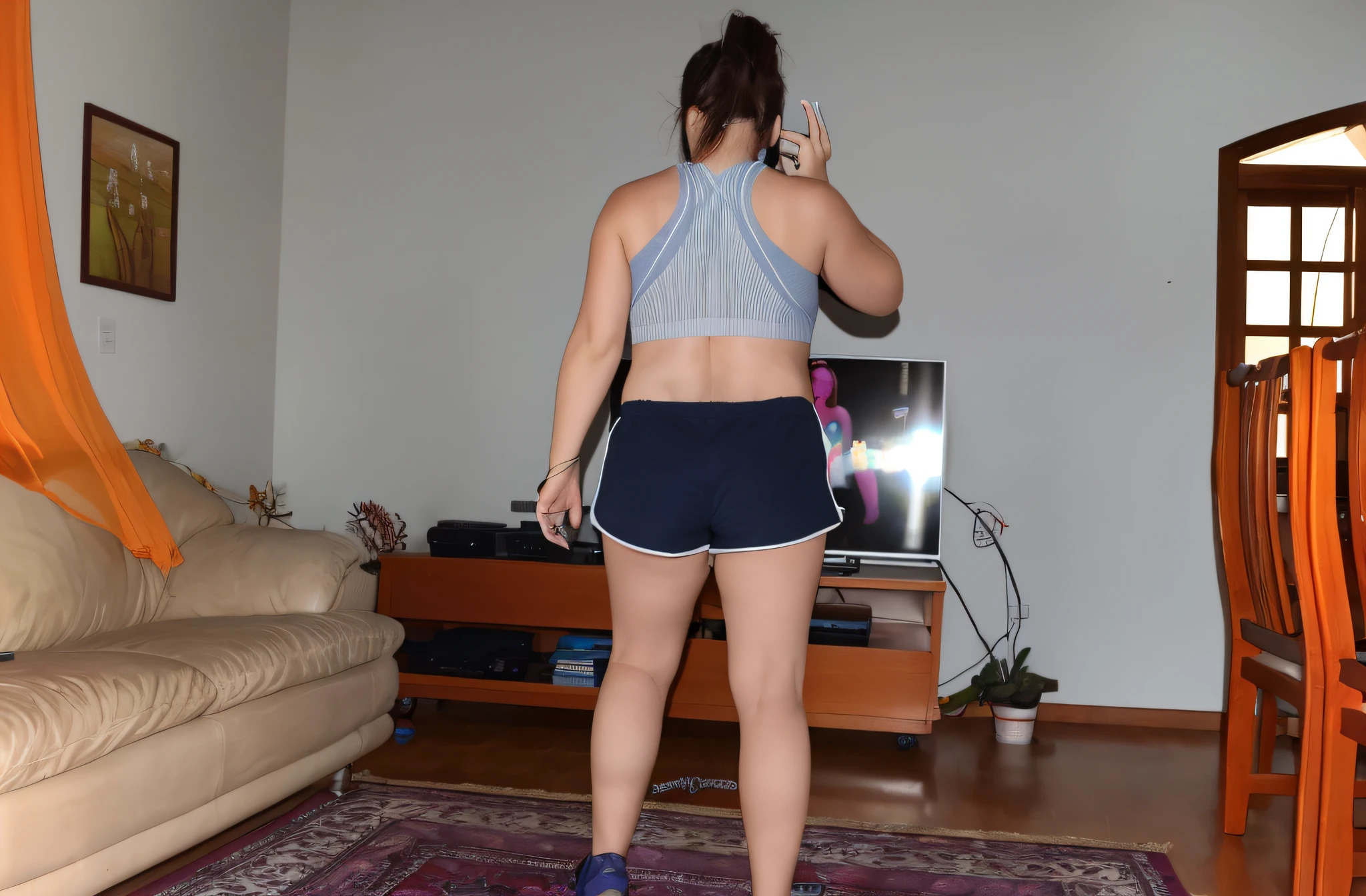 there is a woman standing in a living room with a remote control, sport bra and dark blue shorts, sport bra and shorts, back pose, tiro longo de costas, tiro longo das costas, from the back, seen from back, crescimento total a partir das costas, foto ainda de vista posterior, costas arqueadas, tiro pelas costas, em pleno crescimento a partir das costas