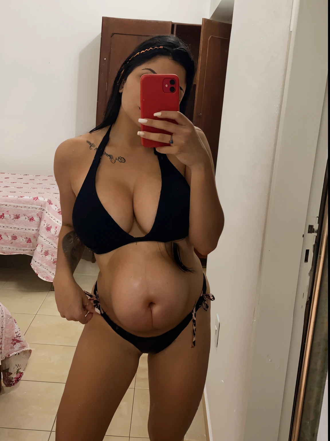 young woman with long black hair pregnant with medium belly taking photo in her room