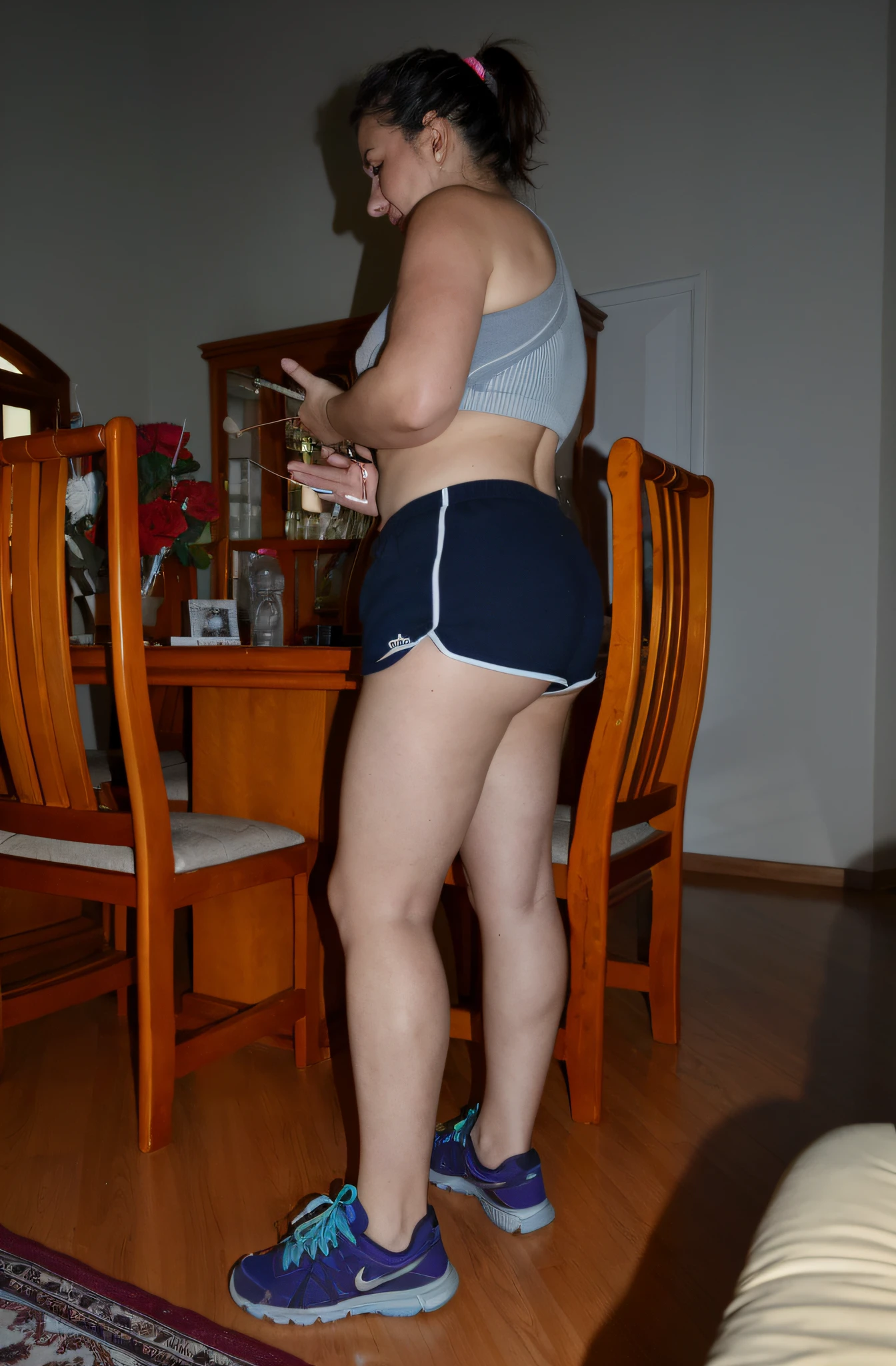 there is a woman standing in a room with a cell phone, sport bra and dark blue shorts, Bermuda, Tiro lateral, coxas expostas!!!, legs visible, coxas expostas, pose lateral, pernas grossas, legs and arms, pernas tonificadas, tiro na perna e coxa, coxas!!!! gorgeous, coxas nuas!!!, tiro na perna e no quadril, coxas!!!!!!, tiro longo de costas