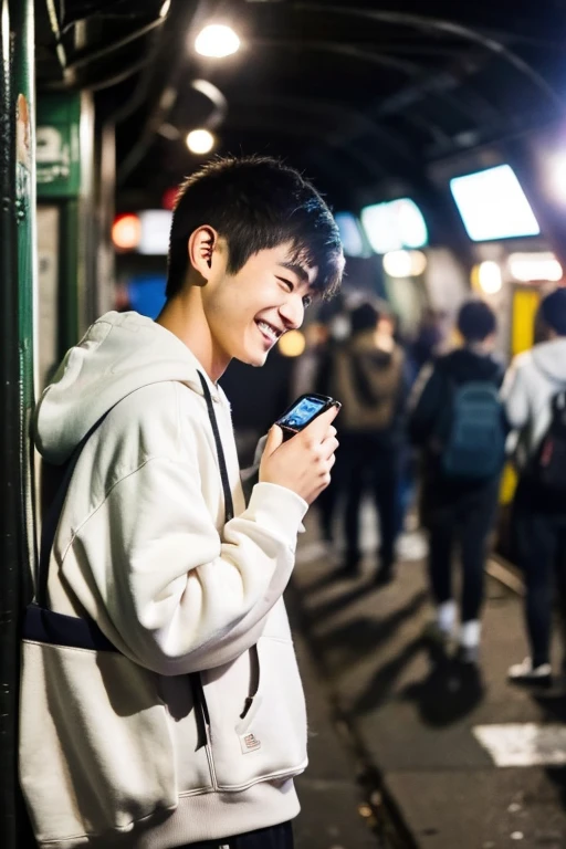 A 20-year-old Japanese man smiles while looking at his smartphone.,There are a lot of people in the underground live venue.,Wearing a white hoodie