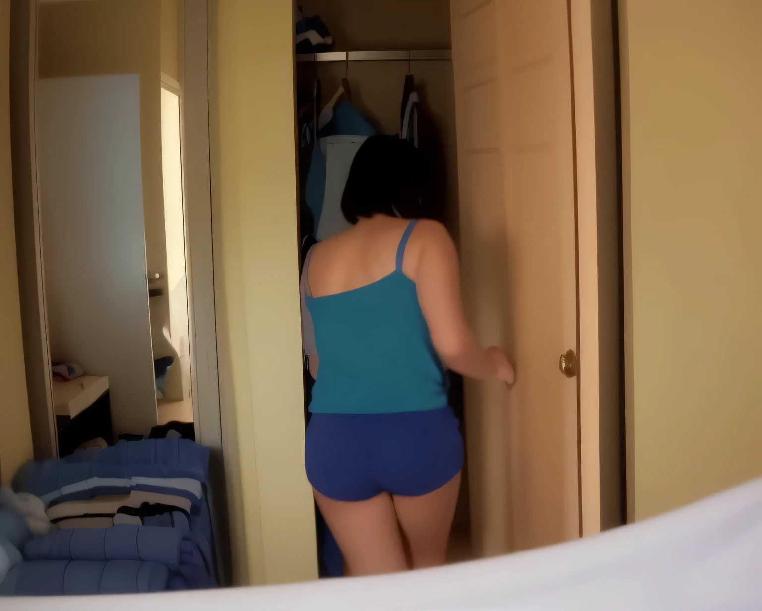 there is a woman in a blue blouse and blue shorts standing in a closet, saindo de um guarda-roupa, tocando suas roupas, hidden camera photo, photo still of behind view, not wearing many clothes, standing in corner of room, blue undergarments, looking from behind, walking away from camera, posando em um quarto, prestes a entrar na moldura da porta, seen from back
