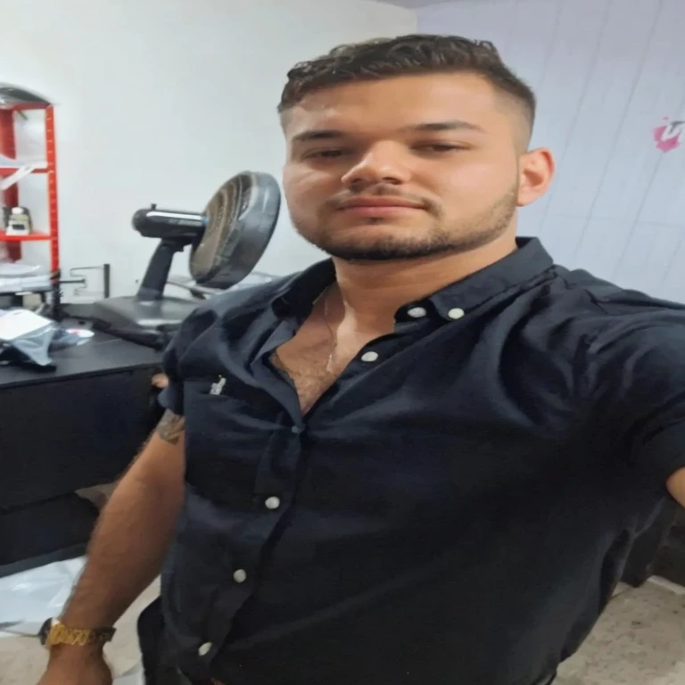 homem arafiado de camisa preta tirando uma selfie em uma barbearia