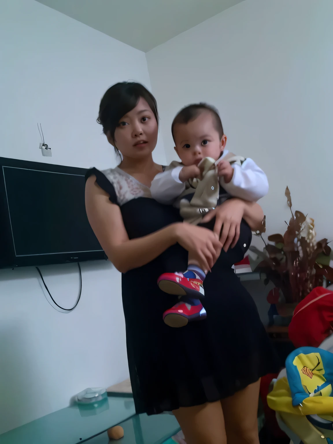 There is a woman holding a  and a boy in the living room, with a chilry very low quality pic,  Meiling, High-resolution scanning, High-resolution scanning, pic, high quality upload, Zimenzheng, There are ivies, jinyiwei, li zixin, from china, a pic, old pic