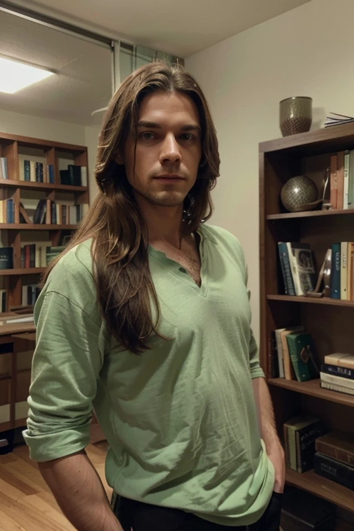 The image features a man with long hair, wearing a green shirt and a white undershirt. He is standing in a room with a bookshelf behind him, which has several books on it. The man appears to be posing for a picture, and his hair is blowing in the wind, giving him a stylish and carefree look.