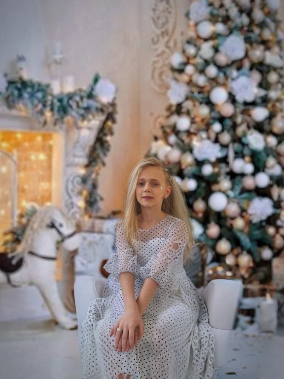 The girl is sitting on a white armchair