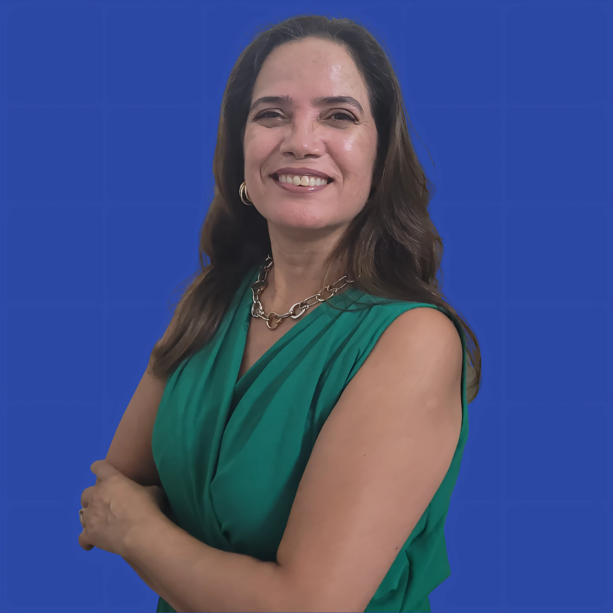 Smiling woman in green dress with arms crossed against blue background, com roupa grega
