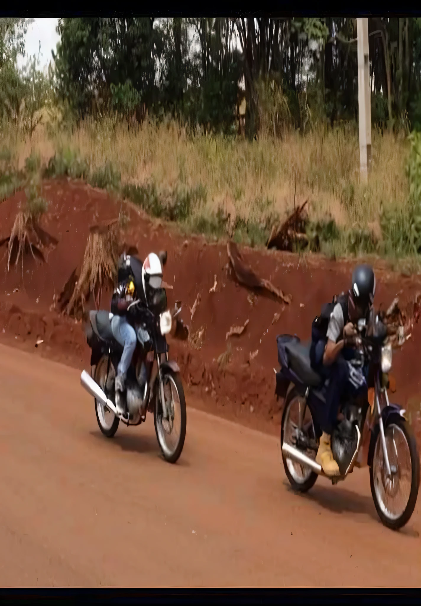 there are two motorcycles that are driving down the road, motocicleta, andando de moto, corrida de motociclistas no inferno, andando de moto down a street, Andar na estrada, excesso de velocidade em motocicleta, Membros da tribo perseguindo, Sri Lanka Mad Max Estilo, chasing action scene, Local people chasing attack, pilotando uma motocicleta, Motocicletas, sem capacete!!!!, sem capacete