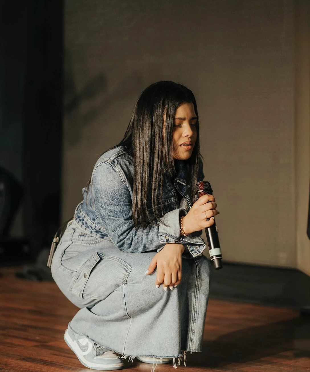 Arafed woman kneeling on the floor with a microphone in her hand., Realizar en el escenario, Realizar, Jovana Rikalo, sitting in front of a microphone, en el escenario, rapping en el escenario at festival, en el escenario, Cindy Avelino, Capturado con Canon EOS R 6, Imagen tomada con Canon EOS R 5, Imagen tomada con Canon EOS R5