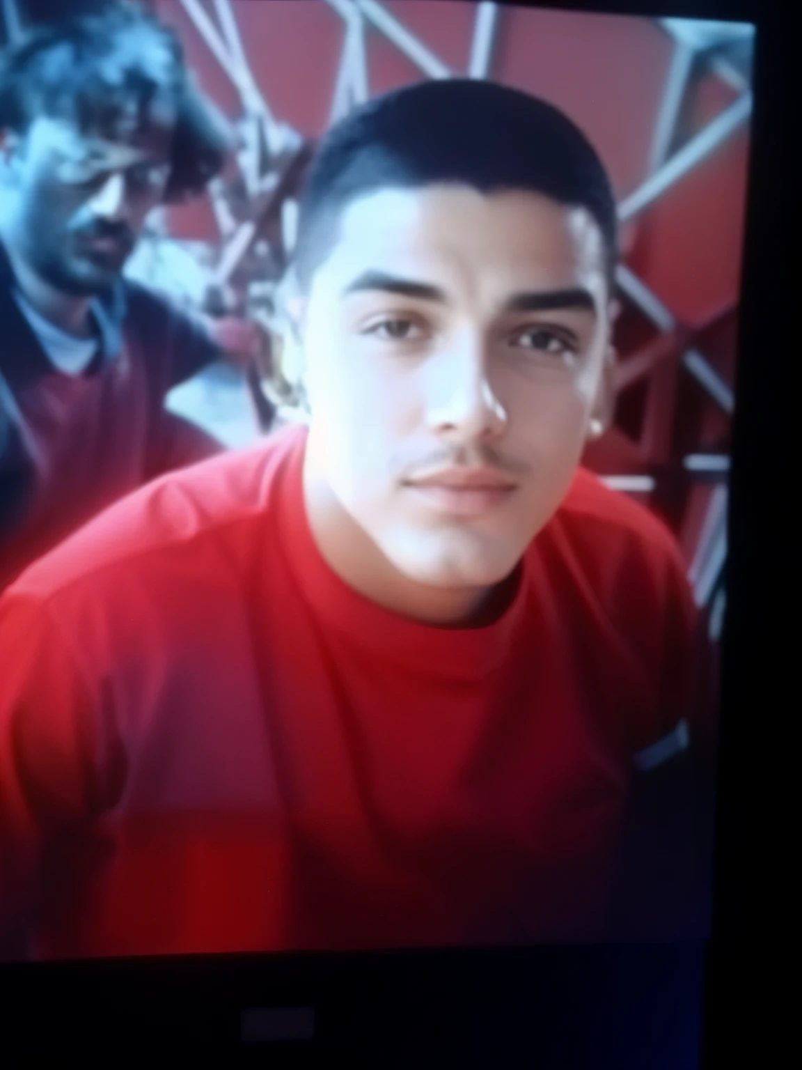 there is a man on the television screen in a red shirt, em torno de 1 9 anos, imagem de qualidade muito baixa, tiradas no final dos anos 2000, 18 anos, cerca de 20 yo, taken in the early 2020s, foto de perfil, tiradas em meados dos anos 2000