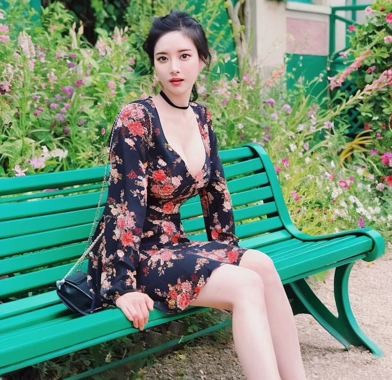 there is a woman sitting on a bench in a garden, korean women's fashion model, cute elegant pose, dilraba dilmurat, floral clothes, bae suzy, dressed in a flower dress, beautiful south korean woman, gorgeous young korean woman, attractive pose, xintong chen, flower dress, beautiful young korean woman, wearing a long flowery dress, korean girl