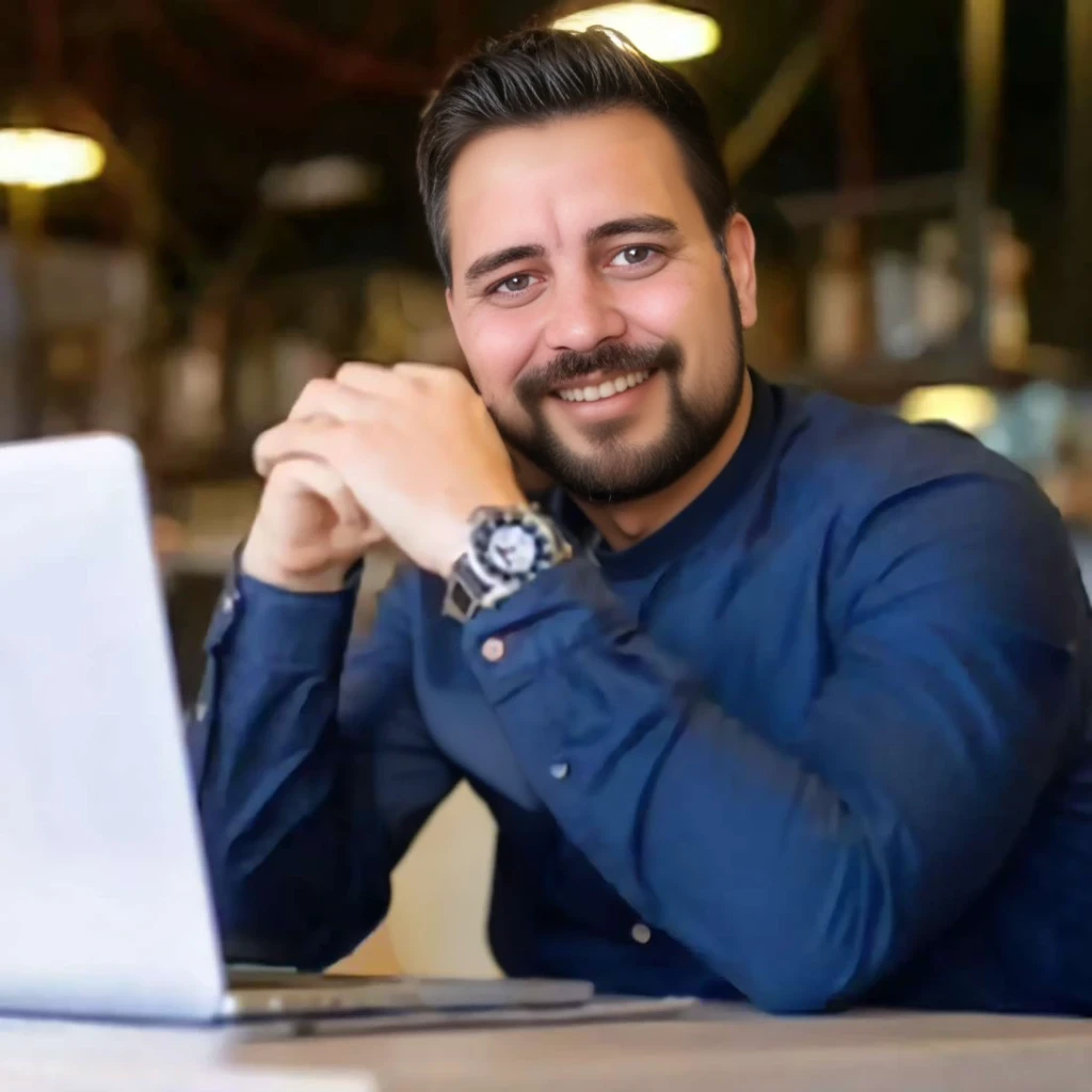 (office background:1.5), Homem branco, (barba longa:1.2), barba lenhador, barba cheia, barba volumosa, barba grande, careca, pouco cabelo, olhos claros, shy smile between open, Homem sentado em uma mesa com um laptop, blusa azul marinho, imagem de perfil, foto profissional, imagem profissional, homem na casa dos 35 anos, imagem de perfil profissional, Postagem no Reddit, codificador criativo com um computador, imagem de avatar, hiper-realista, textura realista, dramatic lighting, (melhor qualidade:1.1), profundidade de campo, HDR, profundidade de campo rasa, luz ampla, alto contraste, luz de fundo, florescer, brilhos de luz, chromatic aberration, sharp focus