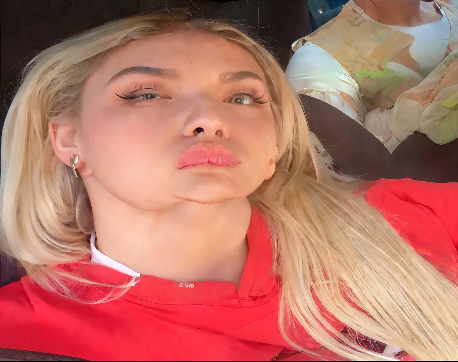 Mujer rubia con los ojos verdes, cabello sedoso y algo ondulado, labios rojos con piel perfecta y piercings en su oreja