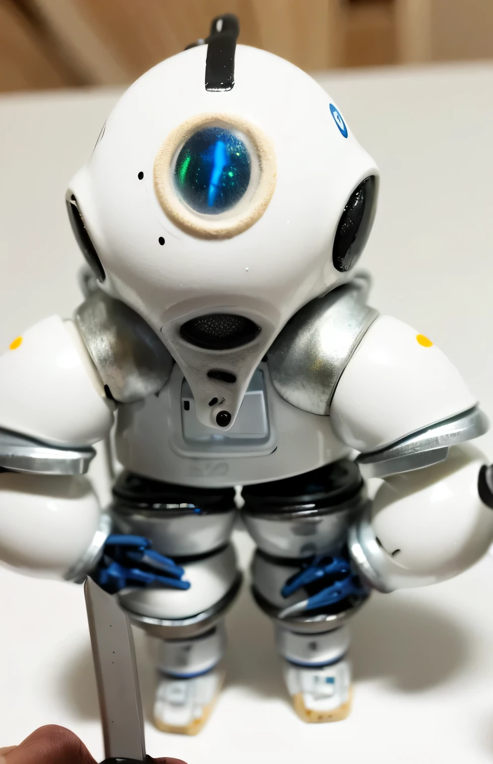 there is a small robot that is sitting on a table, ceramic cyborg, pvc poseable, miniature tachikoma, small astronaut looking up, white biomechanicaldetails, detailed astronaut, detailed humanoid, white robot, robot made of jet parts, white biomechanical details, spaceman standing looking, wheatly from portal 2, porcelain cyborg