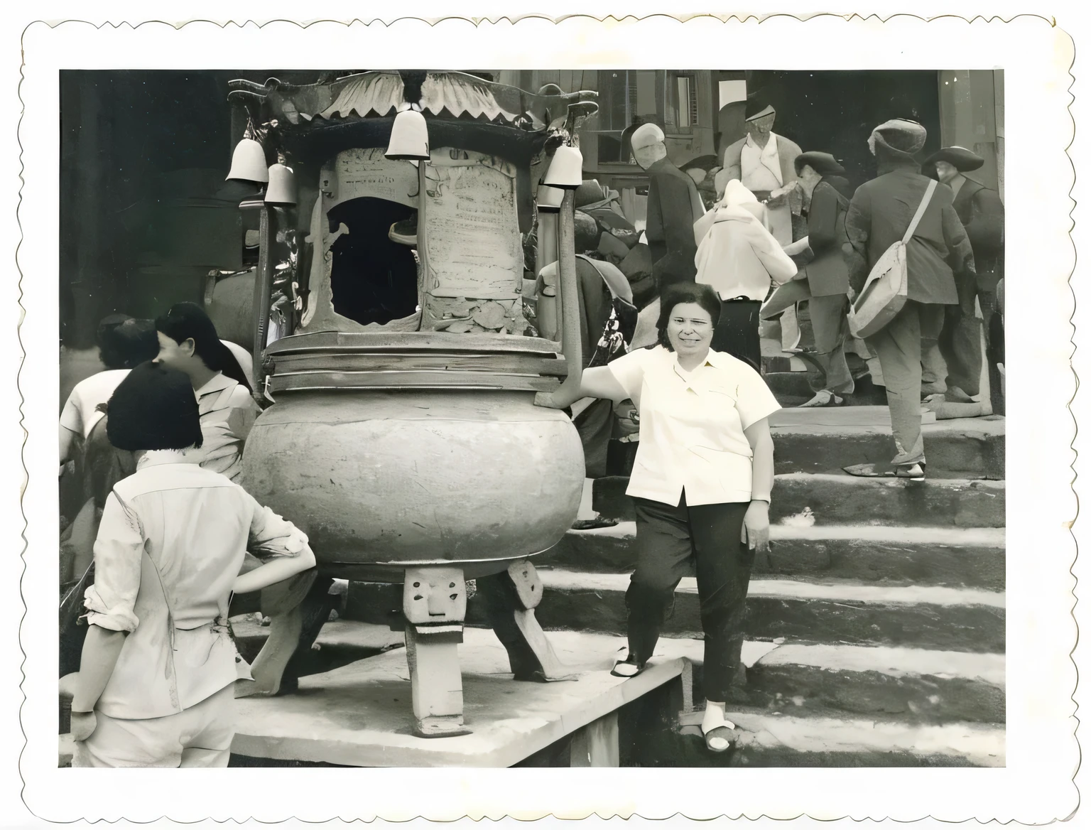 Middle-aged woman wearing white short-sleeved shirt,Wearing black pants,Left hand leaning on tripod,Stand in front of the stairs,There are some elderly tourists,Wearing a backpack,He is holding a fan behind him,There are also two or three tourists on the left,Black and white photo,high resolution