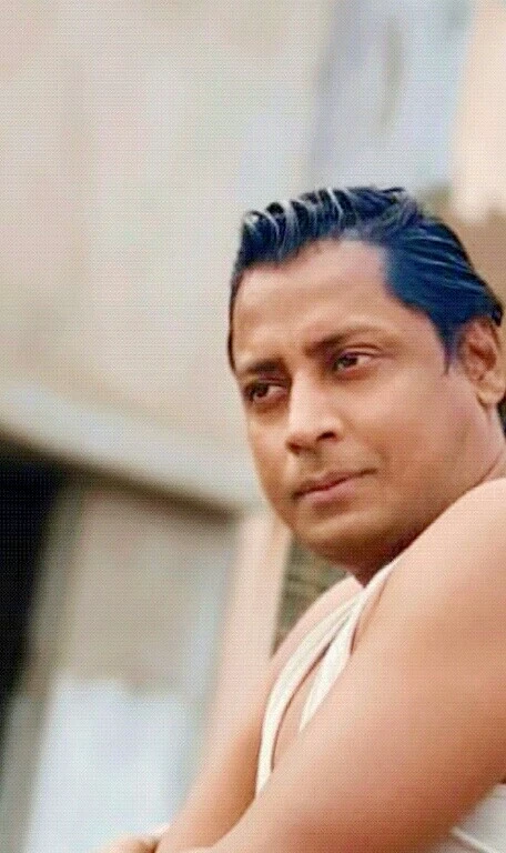 there is a man with blue hair leaning on a brick wall, ranjit ghosh, inspired by Sudip Roy, 4 0 years old man, inspired by Bikash Bhattacharjee, taken in the early 2020s, by Sudip Roy, ashoka tano, profile pic, about 3 5 years old, handsome man