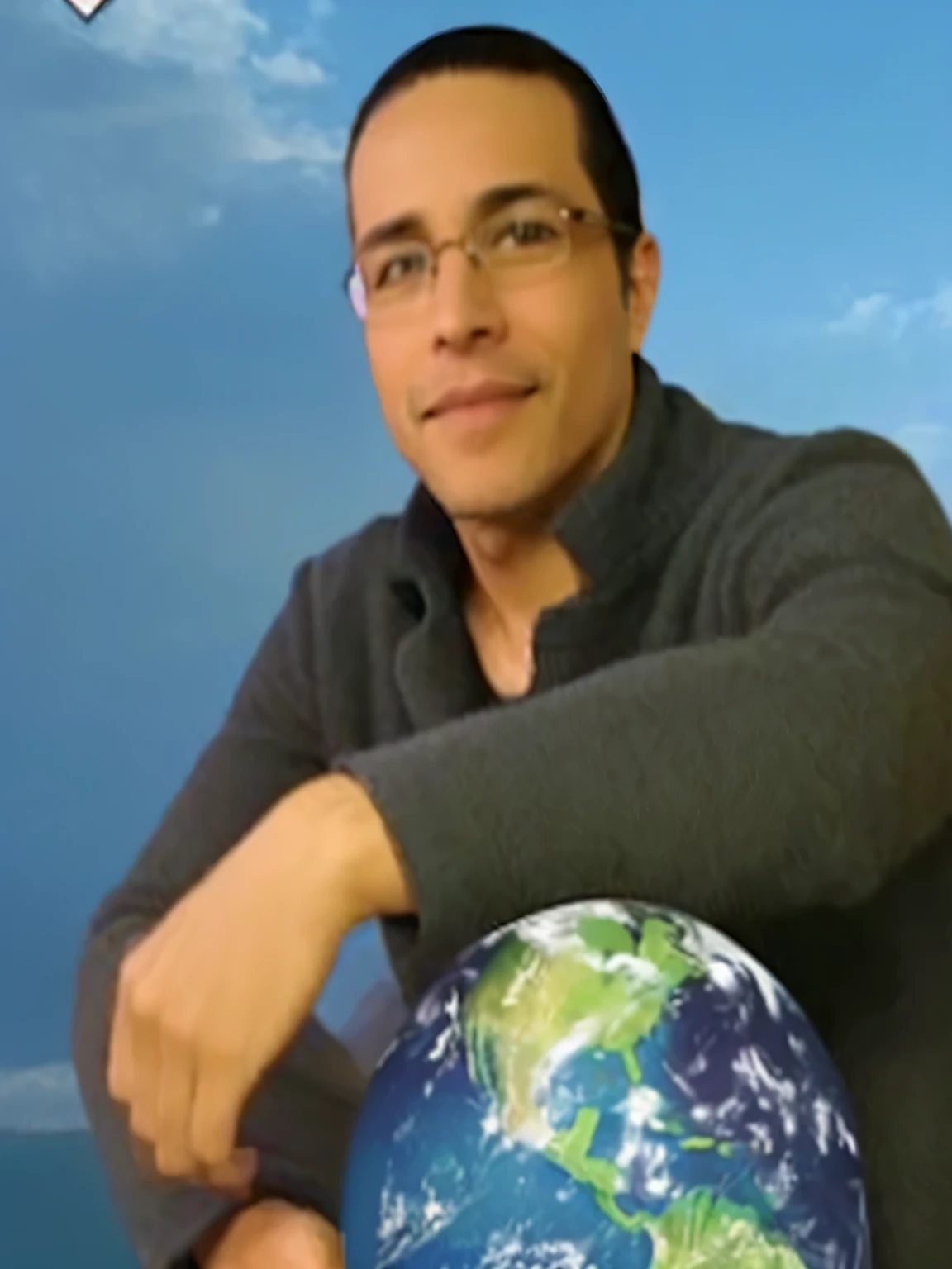 hombre con lentes, smiling holding a globe with a picture of the earth on it, hombre con sueter gris oscuro.