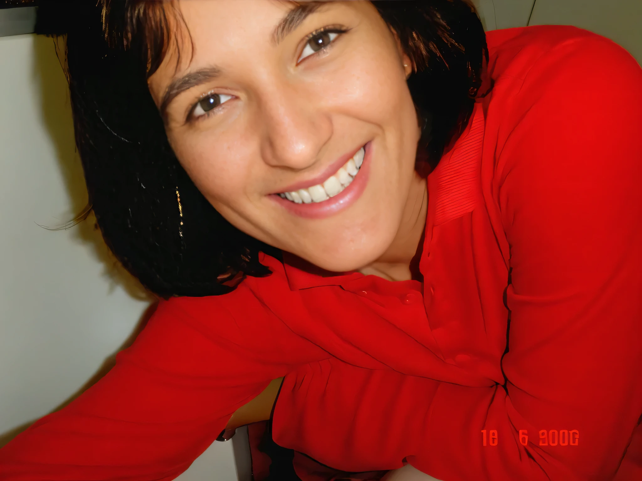 Smiling woman in a red shirt leaning against a counter with a white countertop, foto de perfil. Mulher com pele branca bronzeada e cabelos escuros. ela tem cerca de 35 anos. high resolution, alta qualidade, obra de arte, 8k. Mulher com pele branca bronzeada e cabelos escuros. ela tem cerca de 35 anos. high resolution, alta qualidade, obra de arte, 8k.