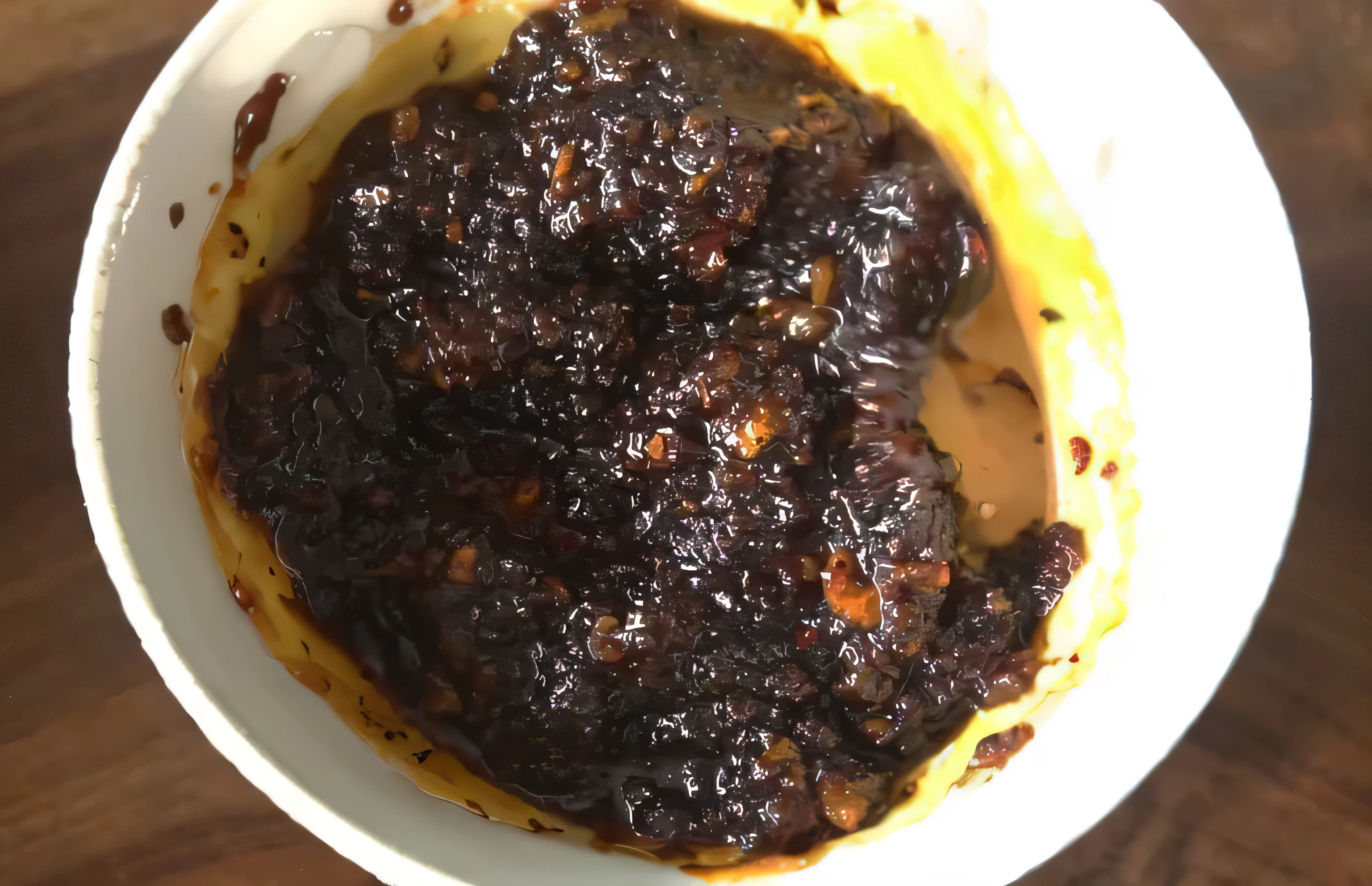 il y a un bol de nourriture posé sur une table, Sauce, des braises jusqu&#39;Ala taille, fondu supprimer, fait de cire et d&#39;huile, cirey, sauce brune, miammy, chili, faire, mystérieuse boue noire, suintement de goo noir, recouvert de goudron, sauce barbecue dégoulinante, cire, miam, ciré, Al&#39;intérieur de l&#39;huile sombre, sichuan